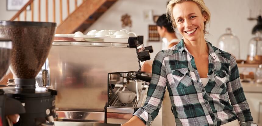 Barista woman smiling by a coffee machine