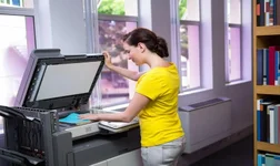 Woman in yellow top scanning a book with a photocopier