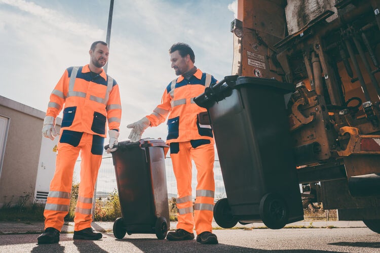 Rubbish men in fluorescent orange collecting waste bins