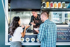 People getting served hot dogs from a food truck