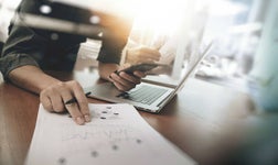 man looking at laptop and paperwork for social media marketing agency for small business